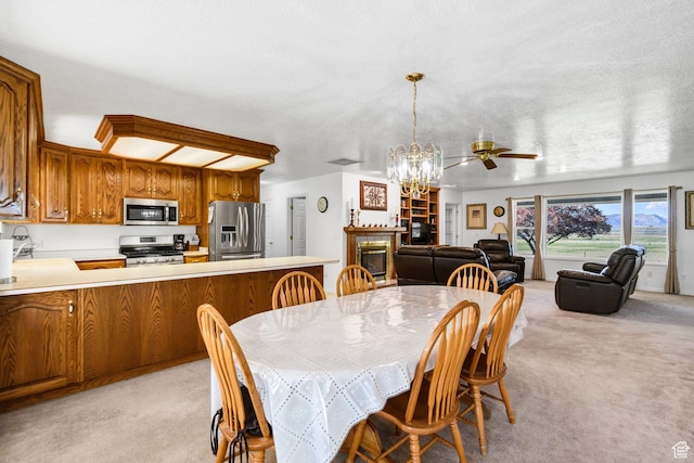 860 S 720 W, Glenwood, UT 84730 - dining space with light colored carpet, a chandelier, a glass covered fireplace, and a ceiling fan