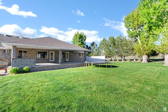 860 S 720 W, Glenwood, UT 84730 - rear view of house featuring a trampoline, brick siding, a lawn, a shingled roof, and a patio area