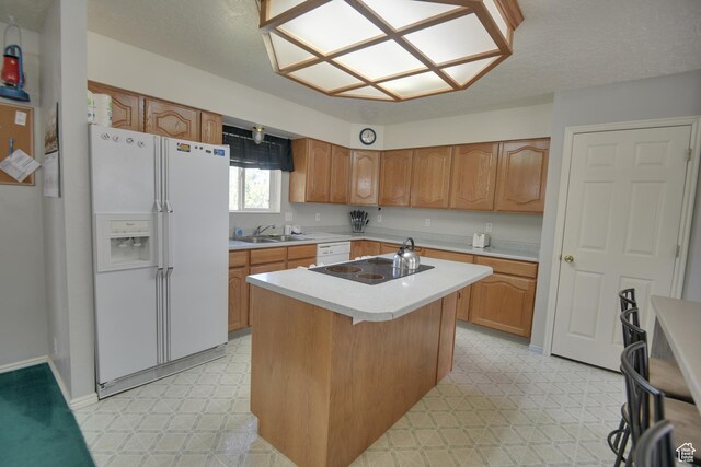 kitchen featuring white appliances, light floors, light countertops, a center island, and a sink