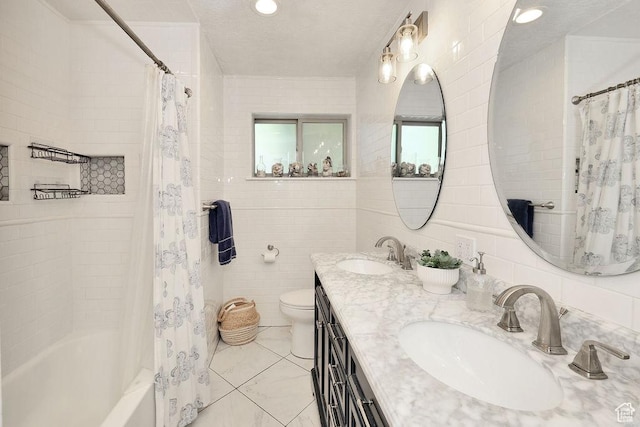 bathroom featuring tile walls, toilet, shower / bath combo with shower curtain, and double vanity