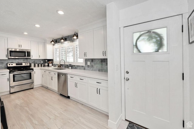 kitchen with appliances with stainless steel finishes, a sink, light countertops, decorative backsplash, and recessed lighting