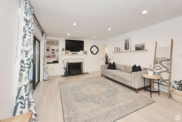 living room with wood finished floors, a fireplace with flush hearth, and recessed lighting