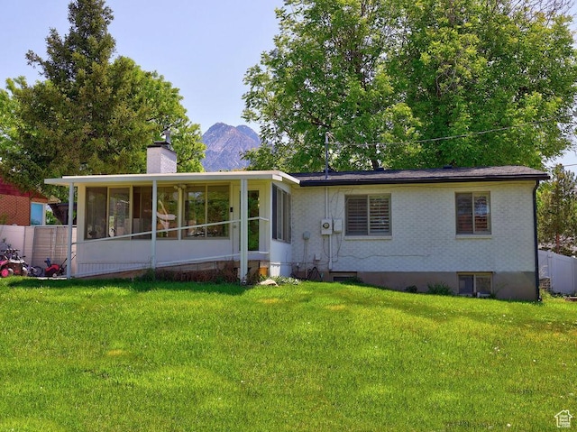 view of front facade featuring a sunroom, a chimney, and a mountain view