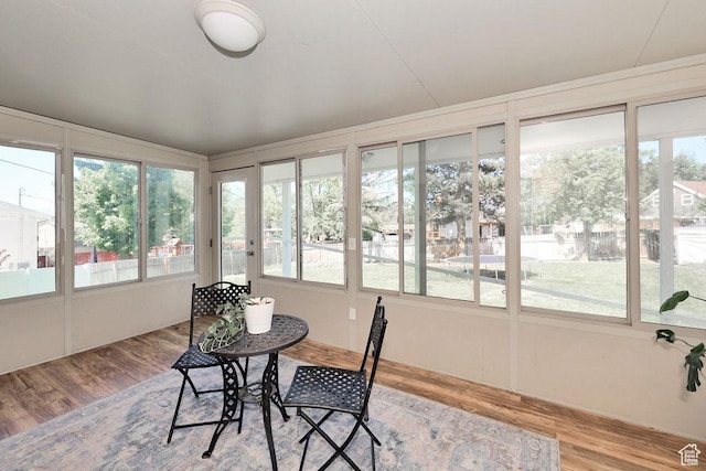 sunroom featuring wood finished floors, plenty of natural light, and a wooden deck