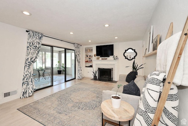 living room with light wood finished floors, a fireplace with flush hearth, and recessed lighting