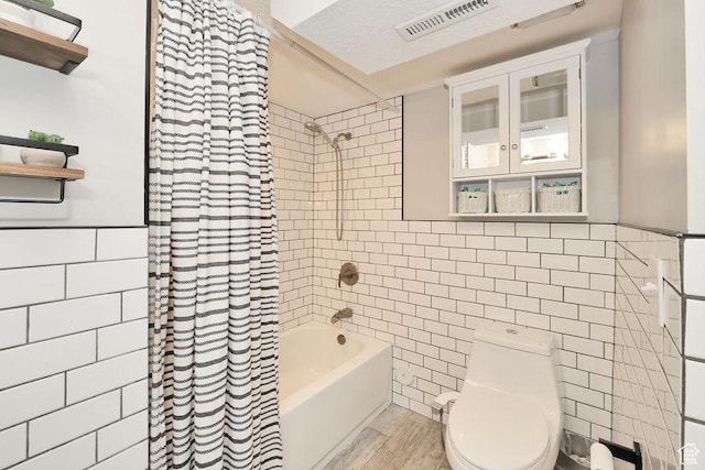 bathroom featuring tile walls, wood finished floors, toilet, and shower / bath combination with curtain