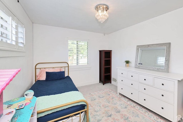 bedroom with light colored carpet, a chandelier, and baseboards