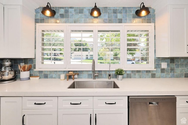 kitchen featuring dishwasher, a sink, tasteful backsplash, and light countertops