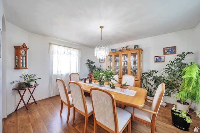 dining area featuring light wood-style floors, a chandelier, and baseboards