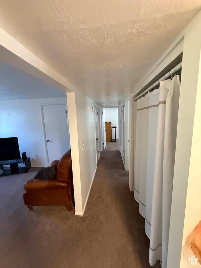 hall with carpet, baseboards, and a textured ceiling
