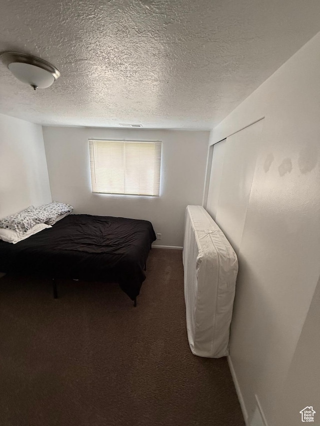 bedroom featuring carpet flooring, a textured ceiling, and baseboards