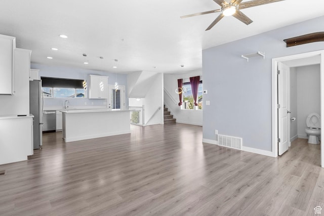834 W Shelton Way, Midvale, UT 84047 - unfurnished living room featuring ceiling fan, recessed lighting, stairway, light wood-type flooring, and a sink