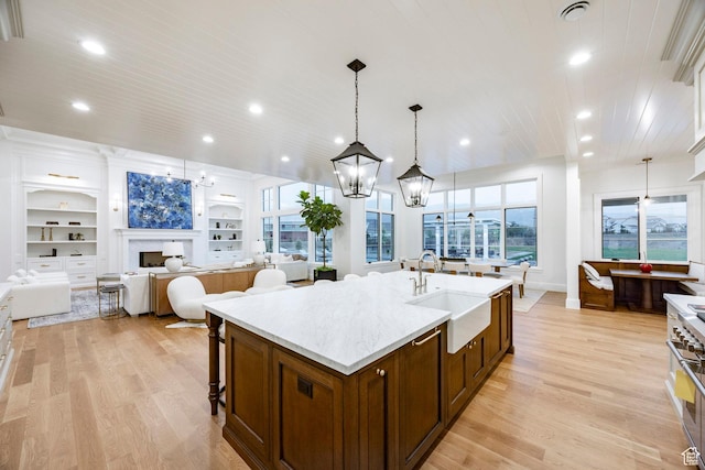 kitchen featuring a sink, a chandelier, open floor plan, light wood-style floors, and recessed lighting