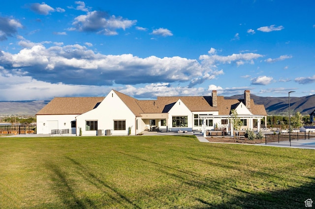 rear view of house featuring a chimney, stucco siding, a patio area, and a mountain view