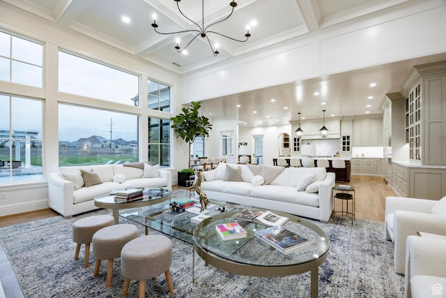 living room with light wood-style flooring, a towering ceiling, plenty of natural light, a chandelier, and beamed ceiling