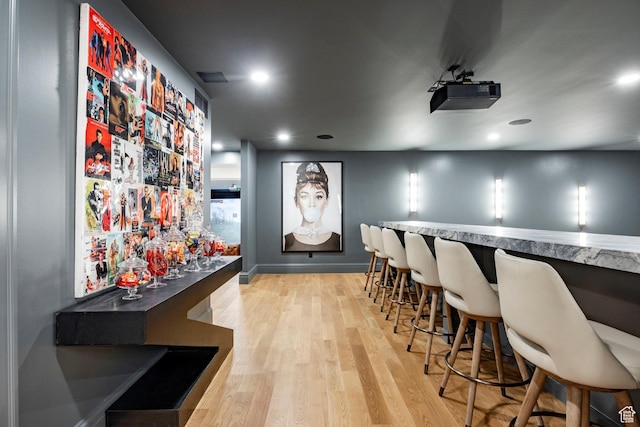 home theater room featuring a bar, light wood-style floors, recessed lighting, and baseboards
