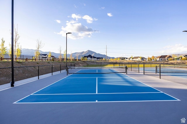 view of tennis court featuring a mountain view and fence