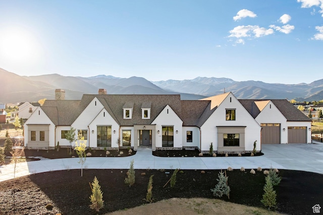 modern farmhouse style home featuring a mountain view, a chimney, driveway, and an attached garage
