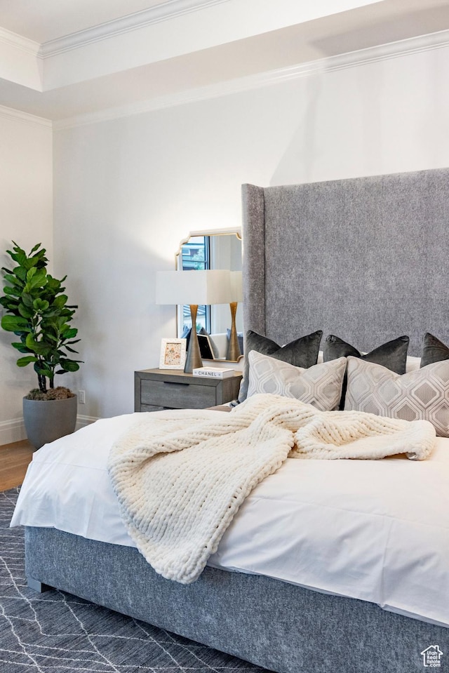 bedroom with crown molding, wood finished floors, and baseboards