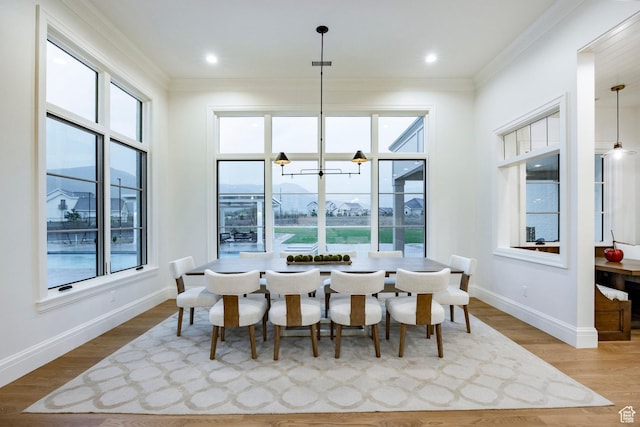 dining room with ornamental molding, plenty of natural light, baseboards, wood finished floors, and a chandelier