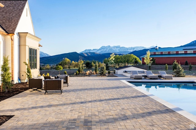 outdoor pool featuring a mountain view, a patio area, an outdoor living space, and central AC