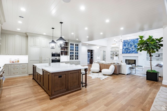 kitchen featuring a sink, light wood finished floors, dark brown cabinets, and recessed lighting