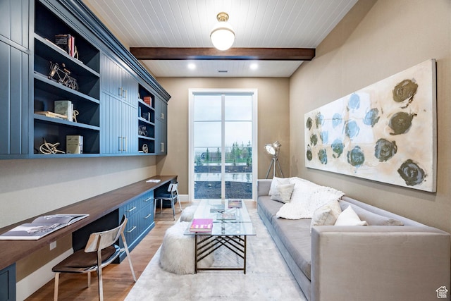 office area featuring built in study area, light wood-style floors, beamed ceiling, and baseboards