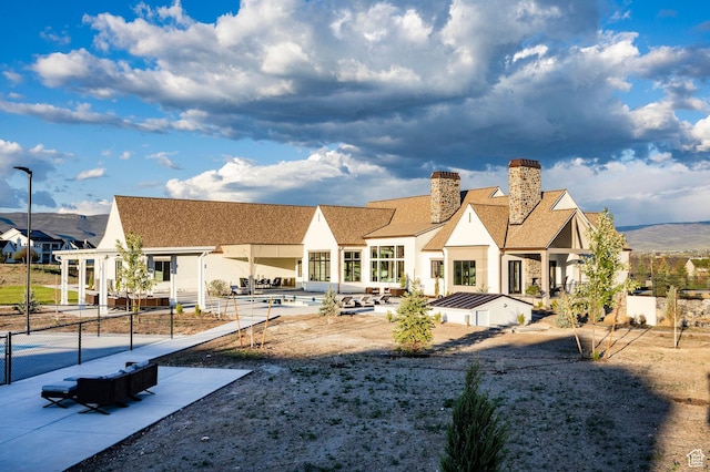 rear view of property with a chimney, a patio, and stucco siding