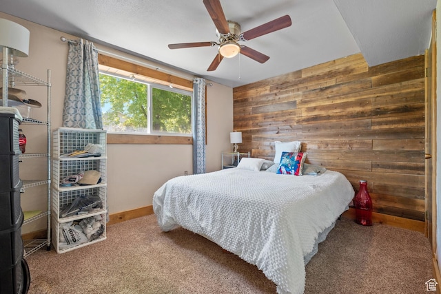 bedroom featuring wood walls, carpet flooring, baseboards, and a ceiling fan