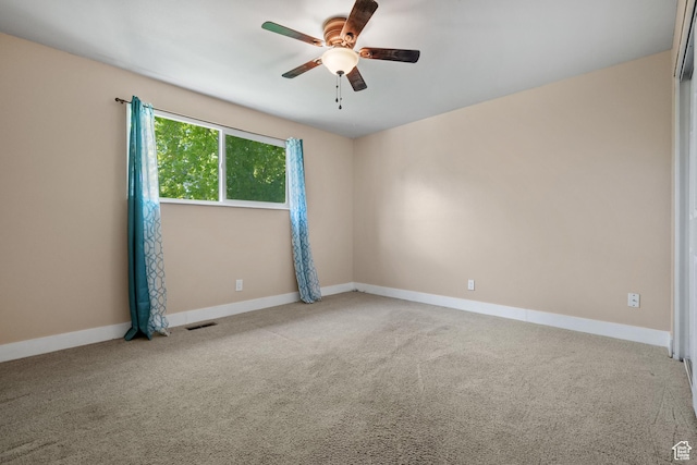 carpeted spare room featuring a ceiling fan and baseboards