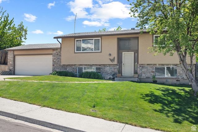 split foyer home featuring stone siding, stucco siding, an attached garage, a front lawn, and driveway