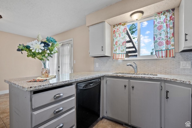 kitchen featuring black dishwasher, a sink, a peninsula, tasteful backsplash, and gray cabinetry