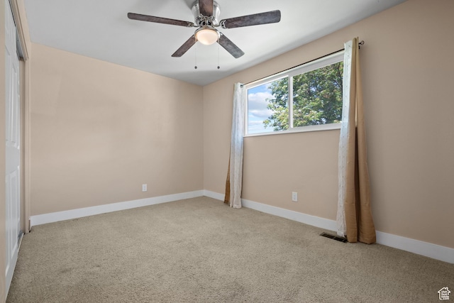carpeted empty room with a ceiling fan and baseboards