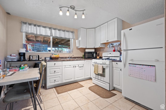 kitchen featuring white appliances, white cabinets, light tile patterned flooring, and a textured ceiling