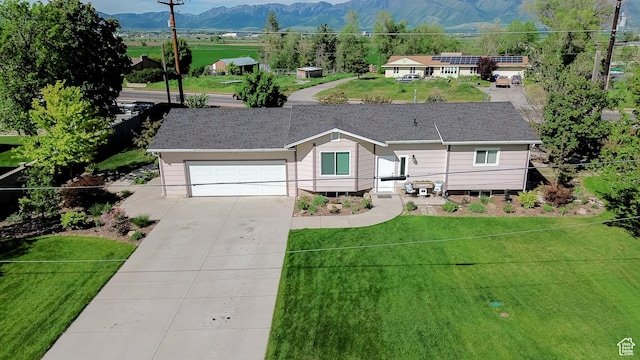 single story home with driveway, a mountain view, a front lawn, and a garage