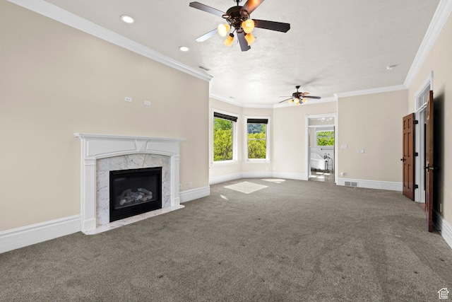 unfurnished living room with a ceiling fan, carpet flooring, a high end fireplace, baseboards, and crown molding