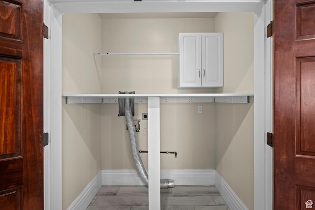 washroom with cabinet space, electric dryer hookup, light marble finish flooring, and baseboards