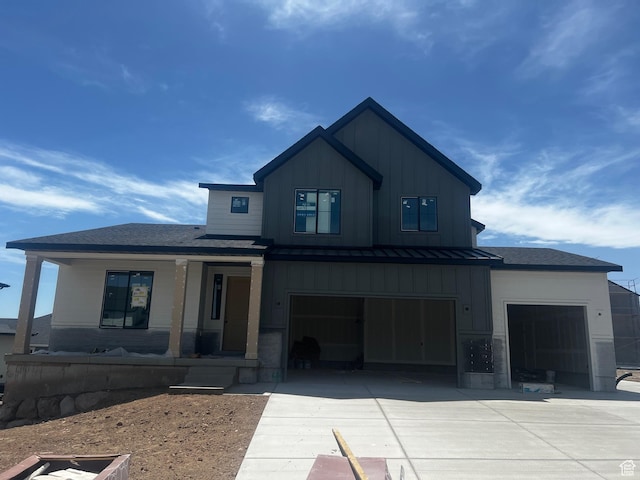 modern inspired farmhouse featuring board and batten siding, a porch, concrete driveway, a standing seam roof, and a garage