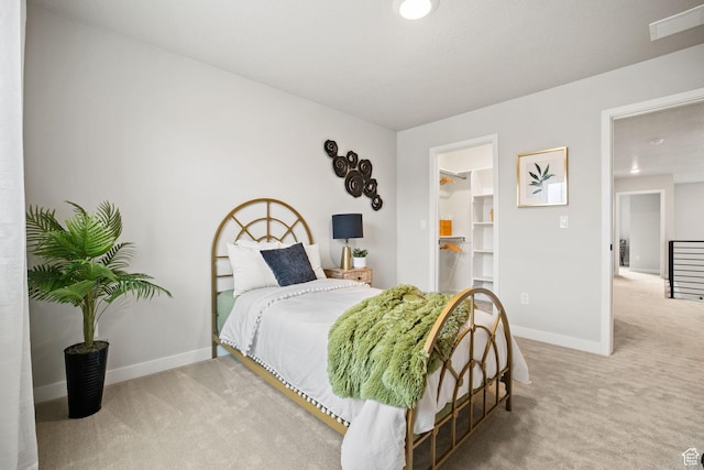 carpeted bedroom with baseboards and a spacious closet