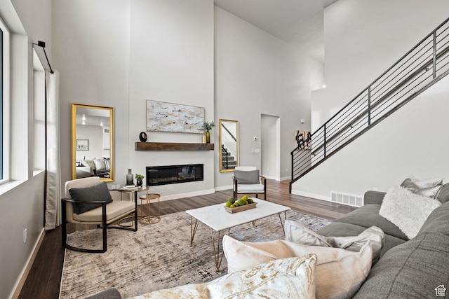 living room with a high ceiling, wood finished floors, stairs, and baseboards