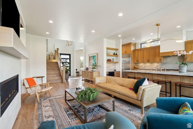 living room with recessed lighting, stairway, a glass covered fireplace, and light wood-style flooring