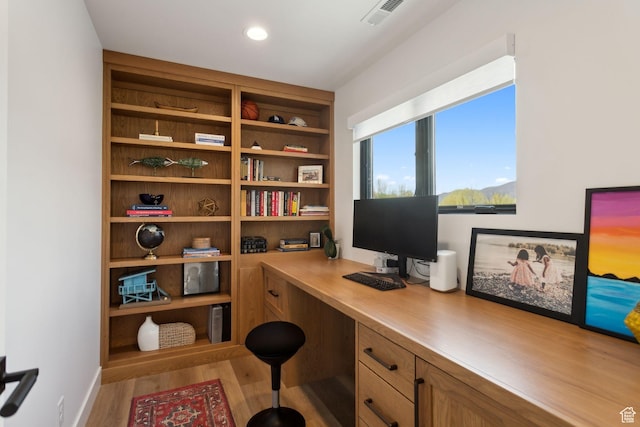 home office with wood finished floors, built in desk, and recessed lighting