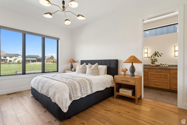 bedroom featuring light wood-type flooring, a chandelier, and baseboards