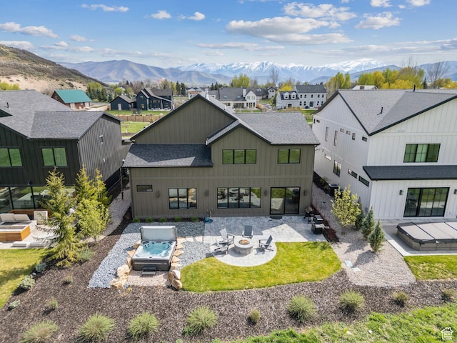 back of house featuring a shingled roof, an outdoor fire pit, and a mountain view