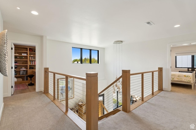 hall with carpet flooring, an upstairs landing, and recessed lighting