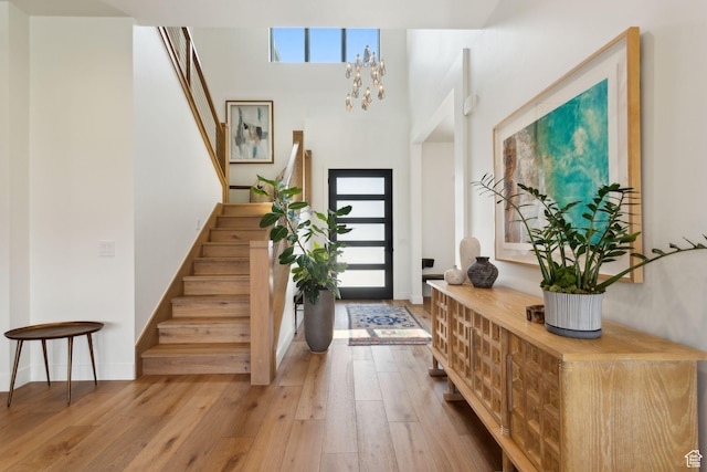 foyer with stairway, hardwood / wood-style floors, baseboards, and a chandelier