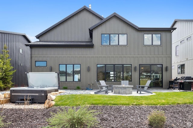 back of property with a fire pit, a patio, a hot tub, and board and batten siding