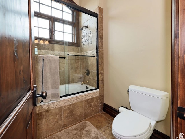 full bath featuring baseboards, tiled shower / bath combo, toilet, and tile patterned flooring