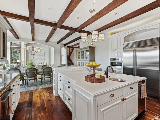 kitchen featuring a chandelier, a sink, appliances with stainless steel finishes, beamed ceiling, and dark wood-type flooring