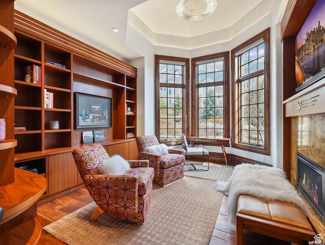 living area with a high end fireplace, plenty of natural light, and wood finished floors